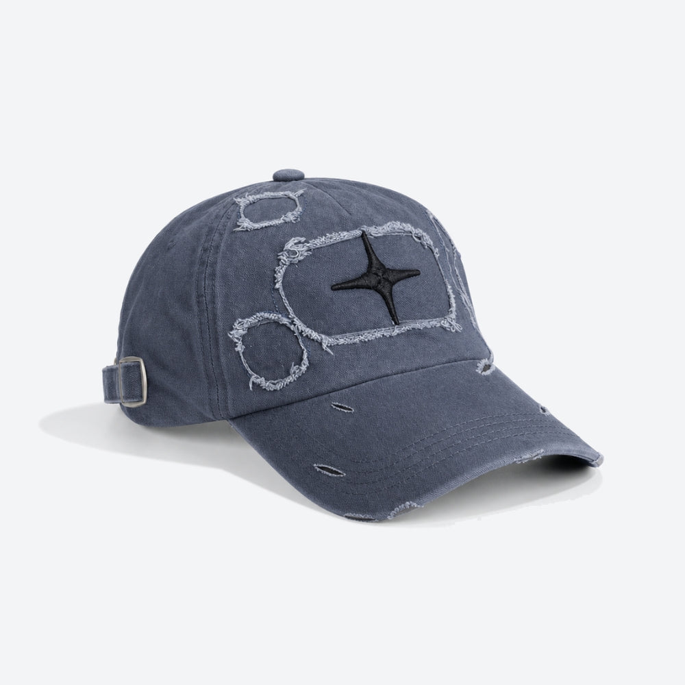 A distressed navy blue baseball cap with a black embroidered star on a white outlined graphic patch on the front, featuring a side buckle strap and frayed details.
