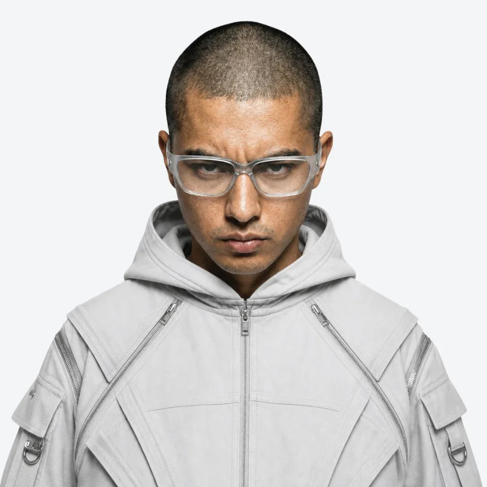 VYSER clear rectangular eyewear on model in light gray techwear hoodie with zipper details, minimalist streetwear style.