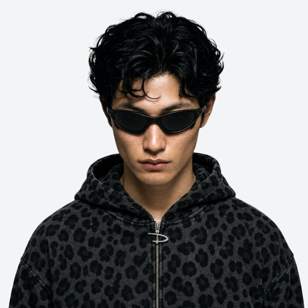 Person wearing a black leopard print hoodie and VYSER Sunglasses with a black frame and black lenses on a white background