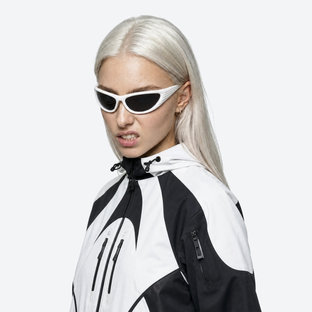 Person wearing a black and white jacket with VYSER White sunglasses with dark lenses on a white background