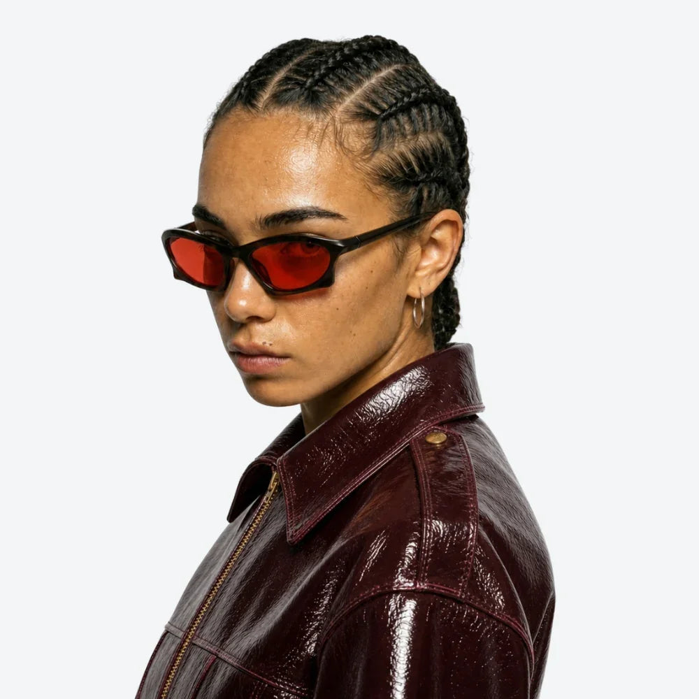 VYSER red-lens cat-eye sunglasses with black frames, styled with a burgundy leather jacket for streetwear edge.
