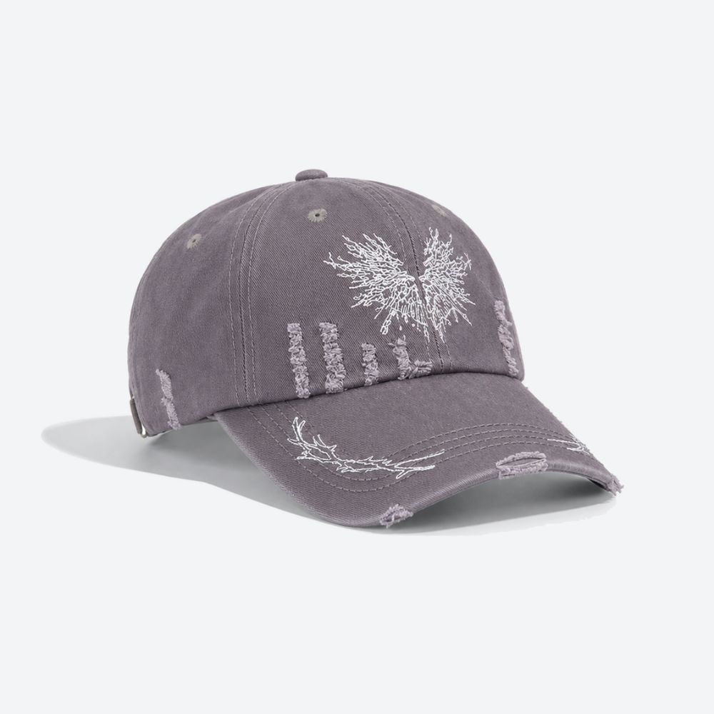 A grey distressed baseball cap with a white embroidered moth, shown from a three-quarter angle revealing the ripped detailing on the crown