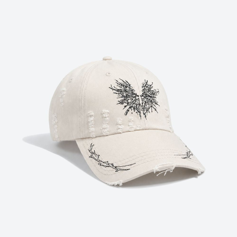 Side profile of a cream distressed baseball cap showing the embroidered thorn branch running along the brim
