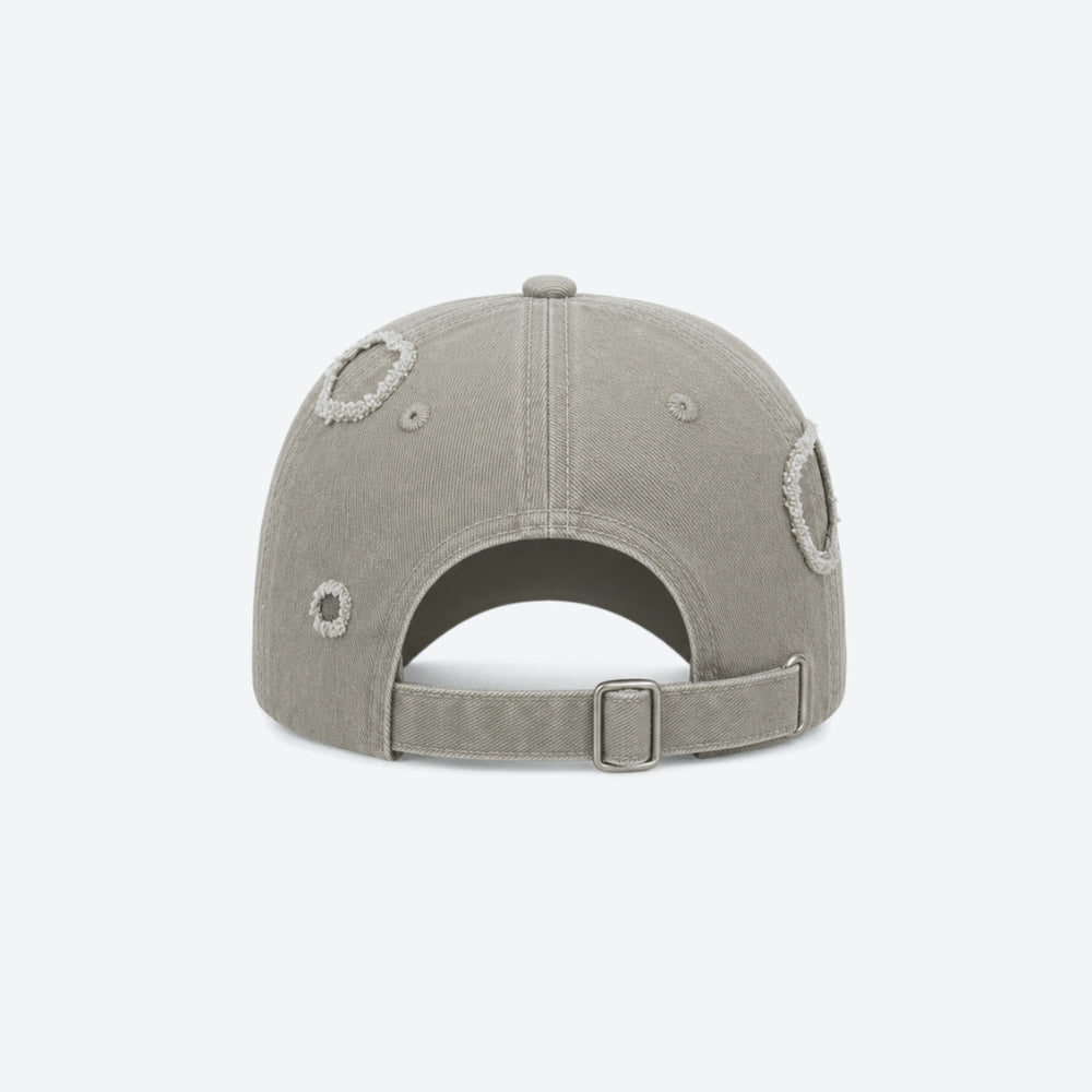 A light gray distressed baseball cap shown from the back, featuring circular embroidery details and an adjustable strap with a metal buckle, set against a plain white background.