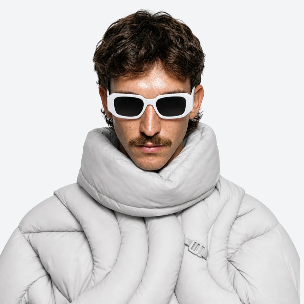 Man wearing a light gray puffer jacket and scarf with VYSER Sunglasses with white frame and black lenses on a white background