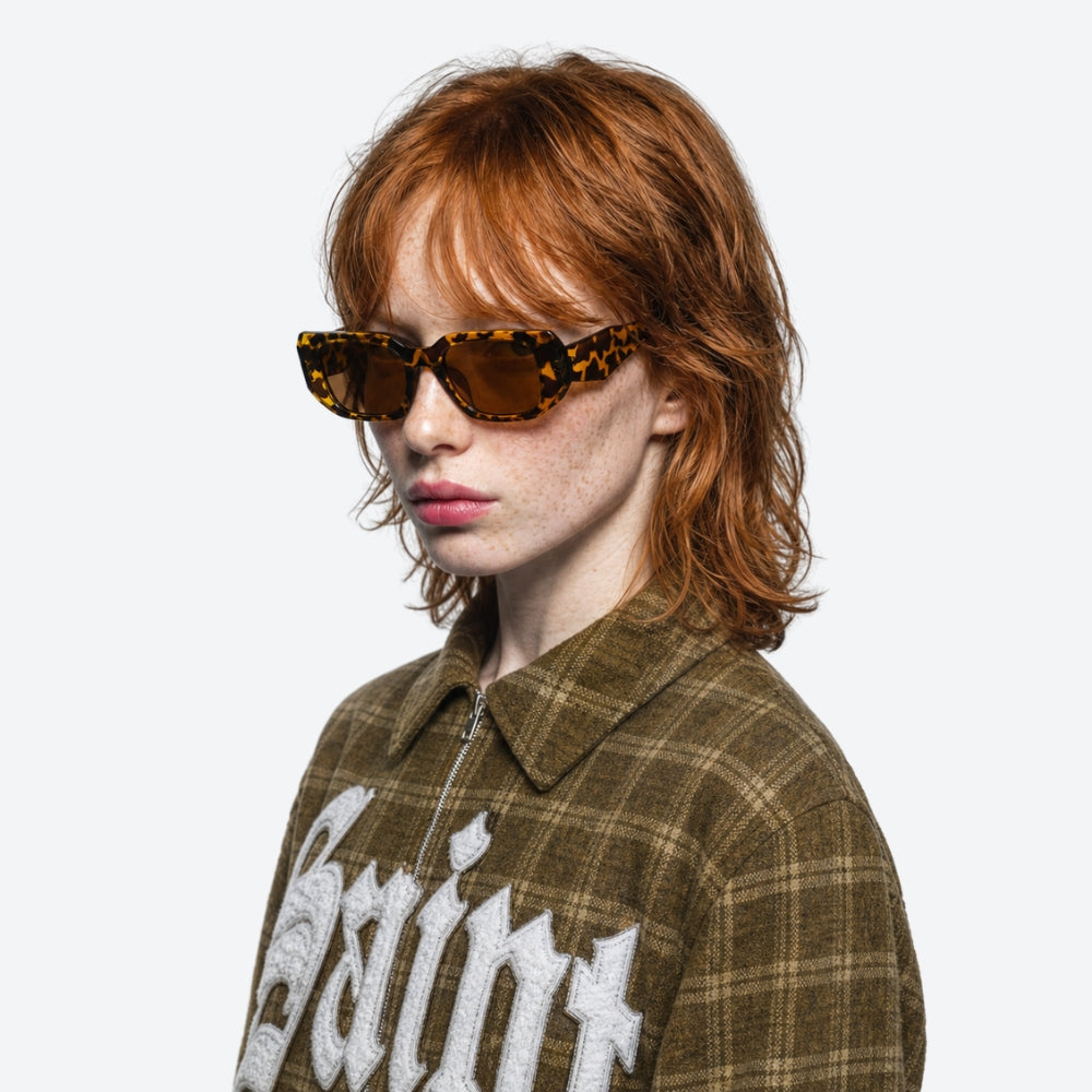 Person wearing VYSER Sunglasses with leopard print frame and brown lenses on a white background