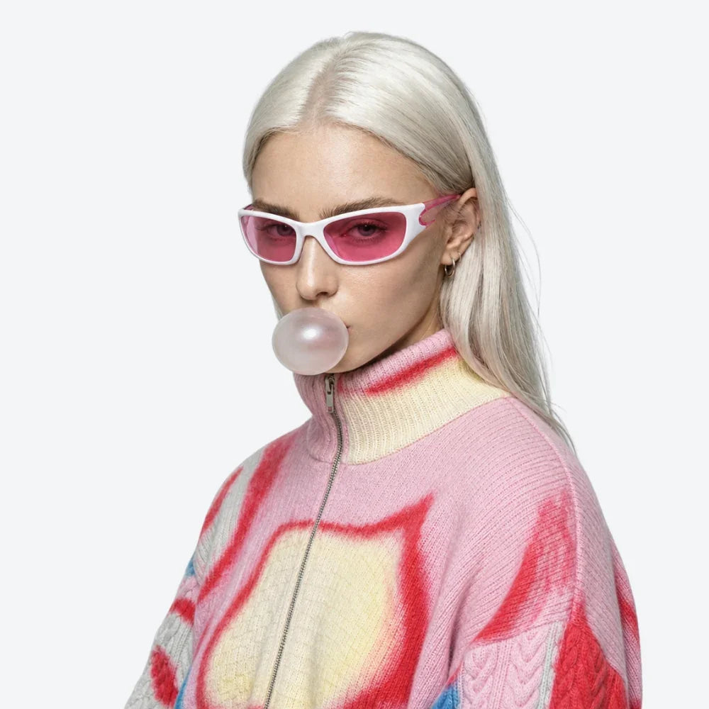 VYSER white frame pink lens sunglasses with sleek cat-eye shape, styled with pastel knit zip-up sweater.