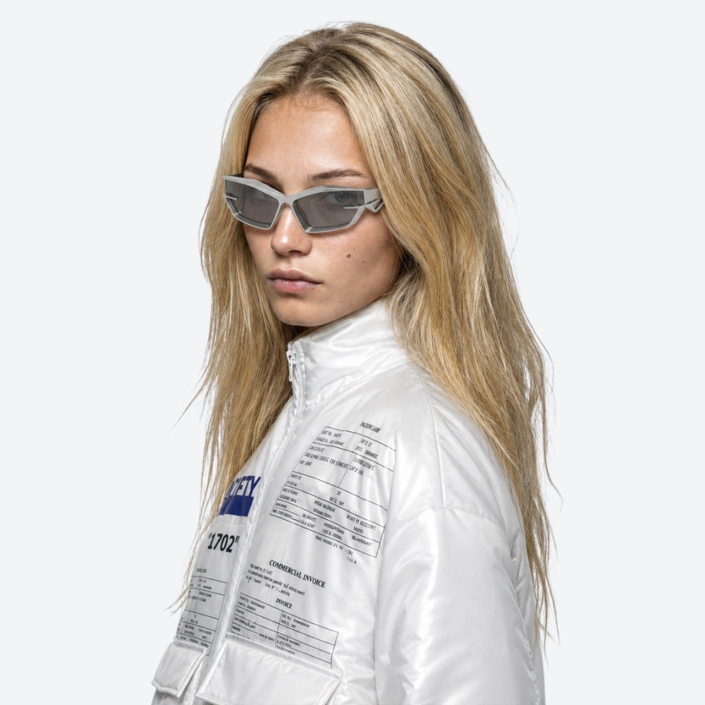 Person wearing a white jacket with text and VYSER Silver sunglasses with a clear frame on a white background