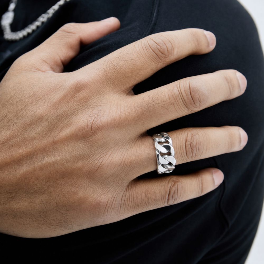 A close-up of a person's hand wearing a wide silver ring with a twisted, textured band design, set against a black shirt background.