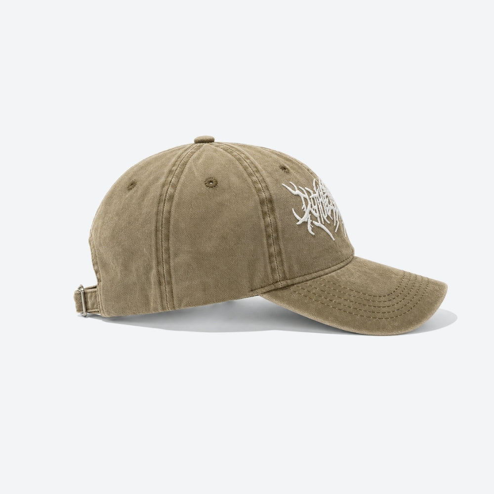 A washed khaki baseball cap with a white embroidered graphic on the side, shown from a three-quarters angle on a light gray background.