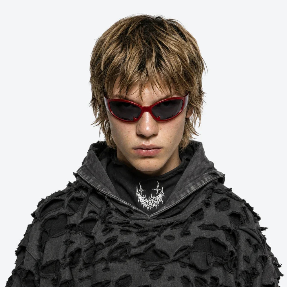VYSER red cat-eye sunglasses with dark lenses, styled with a distressed black hoodie for edgy streetwear look.