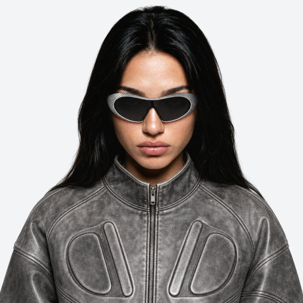 Person wearing a gray leather jacket with VYSER silver Sunglasses with hexagonal lenses on a white background