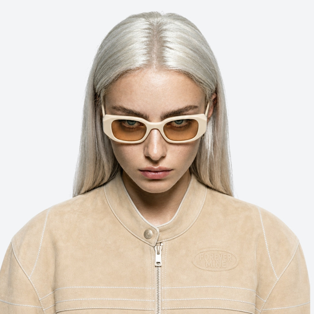 Person wearing VYSER Beige sunglasses with a white frame on a light beige background