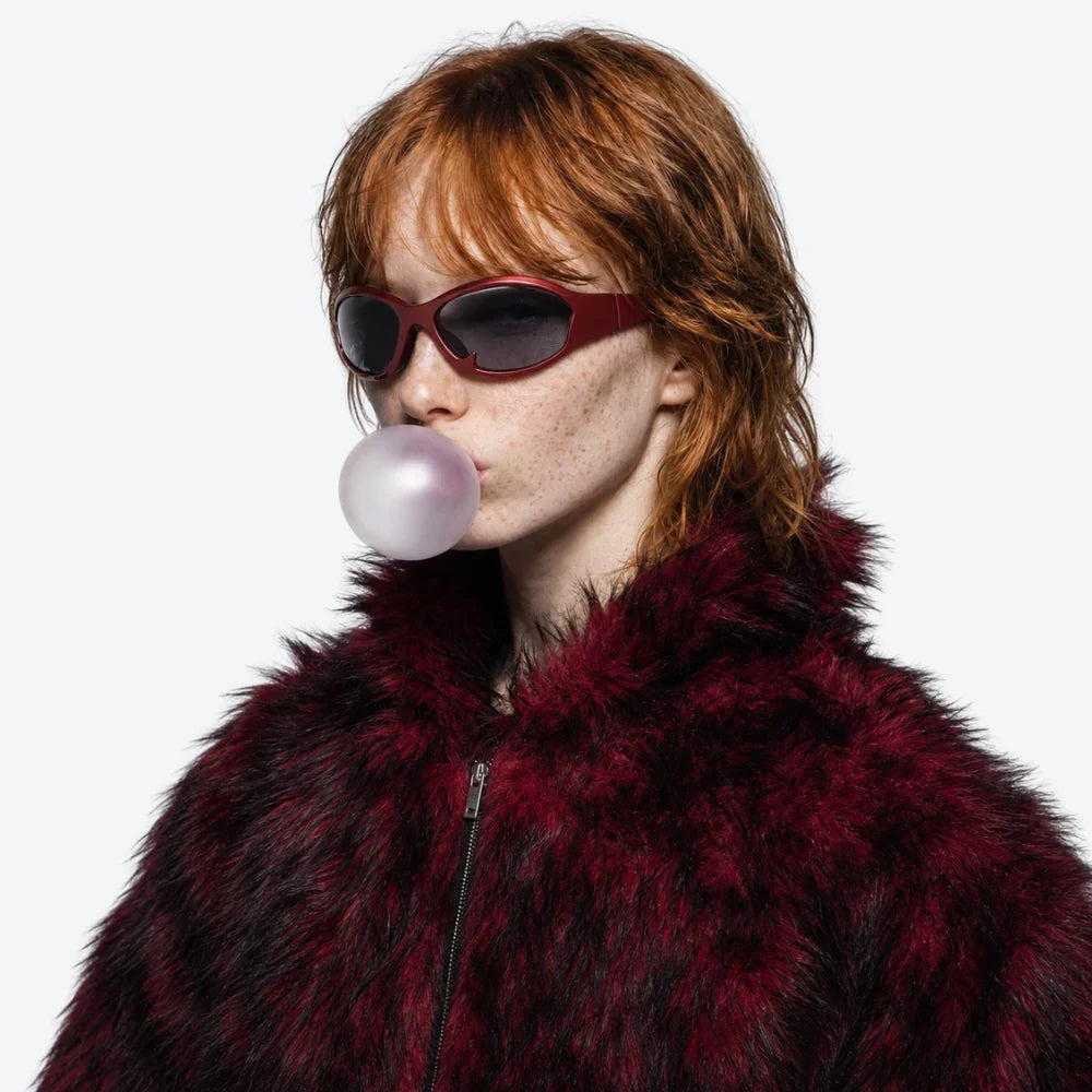 VYSER burgundy fuzzy faux fur jacket with zipper, styled with red oval sunglasses and bubblegum.