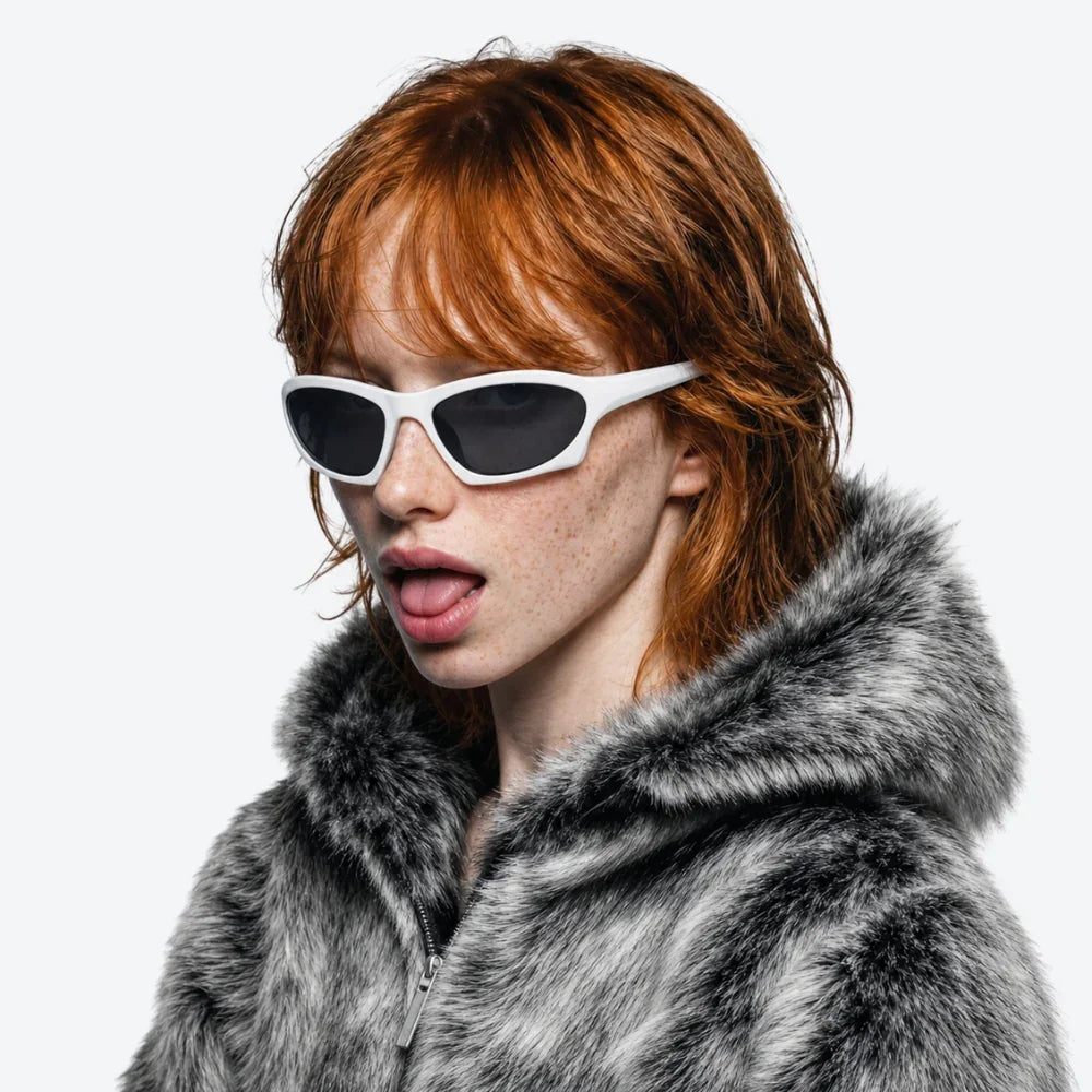 VYSER white cat-eye sunglasses with black lenses, styled with a gray faux fur coat for bold streetwear vibes.