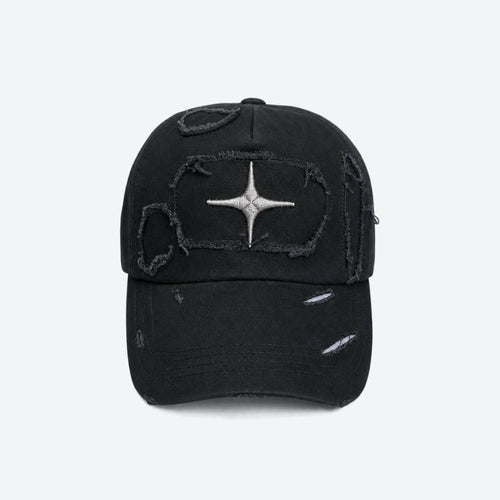 A black distressed baseball cap with a silver metallic starburst patch on the front, set against a plain light gray background.