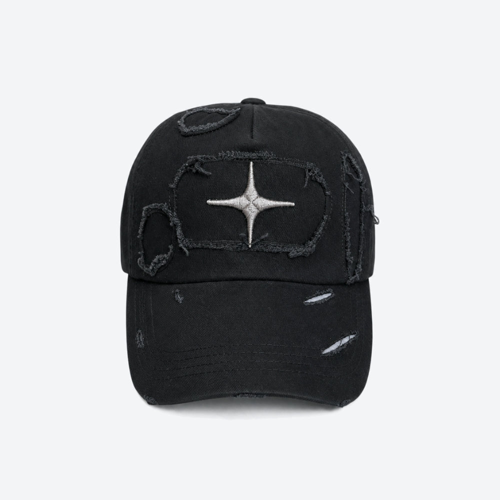 A black distressed baseball cap with a silver metallic starburst patch on the front, set against a plain light gray background.