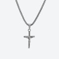 SILVER. A silver crucifix pendant necklace on a matching silver box chain, on a light gray background.