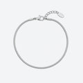 A silver-toned metal snake chain bracelet with a lobster clasp, extension chain, and a blank oval tag, shown on a light gray background.