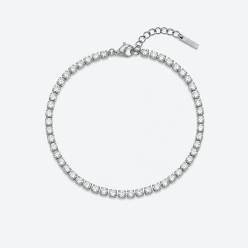 A silver tennis bracelet with a continuous row of clear round-cut stones, featuring a lobster clasp, extension chain, and a small brand tag, shown on a light gray background.