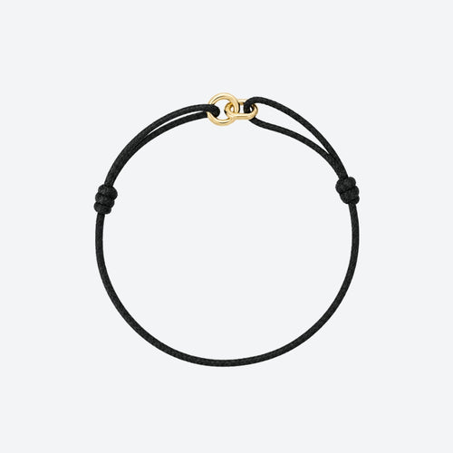 A minimalist black cord bracelet with a small gold interlocking rings clasp, displayed on a clean light gray background.