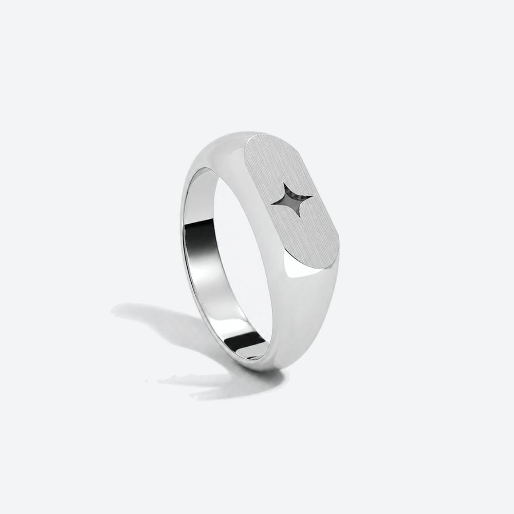 A silver-toned signet ring with a brushed finish and a small star inlay, shown on a light gray background.