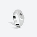 A silver-toned signet ring with a brushed finish and a small star inlay, shown on a light gray background.