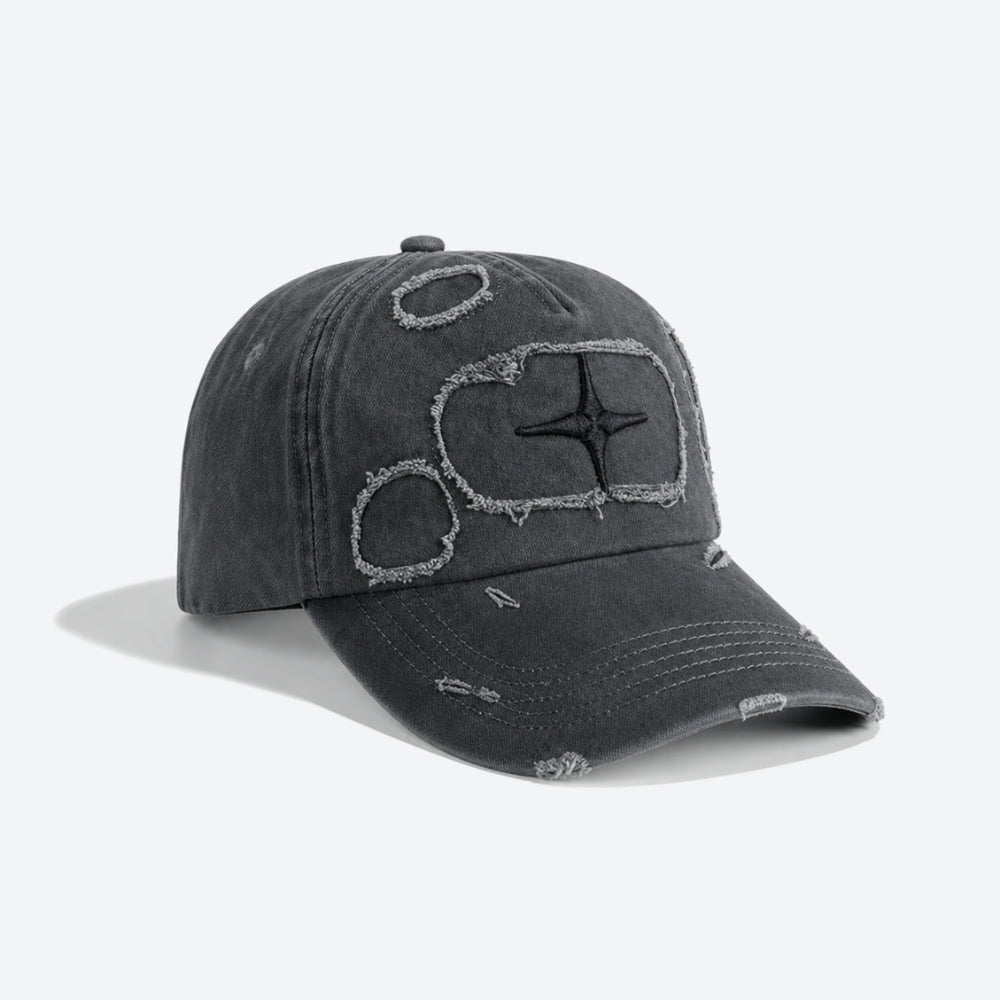 A dark gray washed baseball cap with distressed details and embroidered abstract geometric designs on the front, shown against a light gray background.