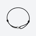 A black adjustable cord bracelet with a polished silver-toned infinity link clasp, displayed on a clean light gray background.