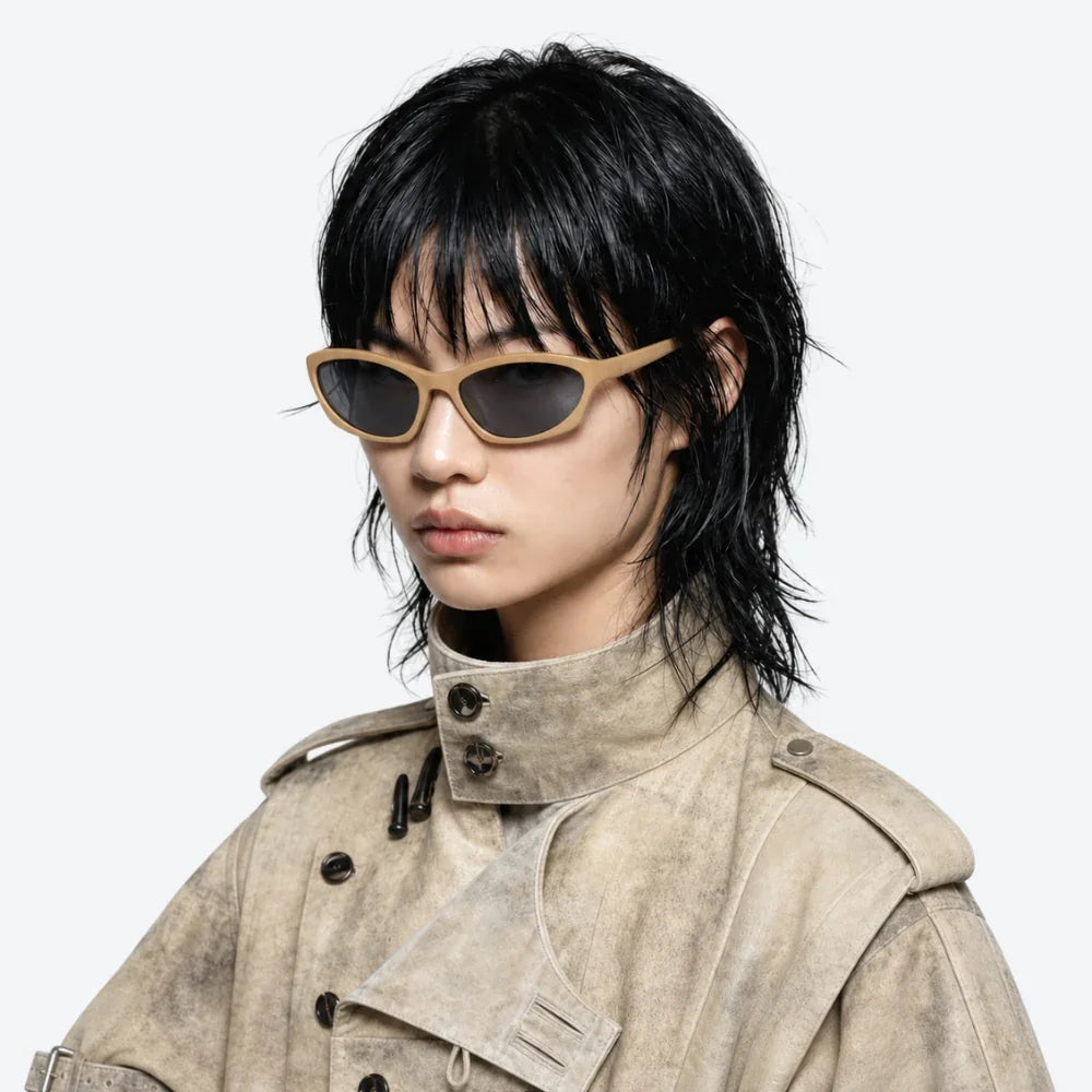 VYSER beige cat-eye sunglasses with dark lenses, styled with a textured beige trench coat for modern streetwear.