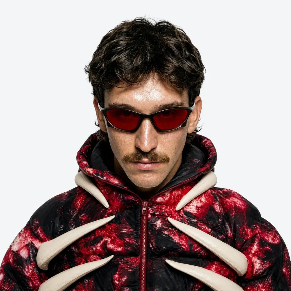 VYSER red-tinted cat-eye sunglasses with black frame, styled with bold red-and-black puffer jacket featuring bone accents.