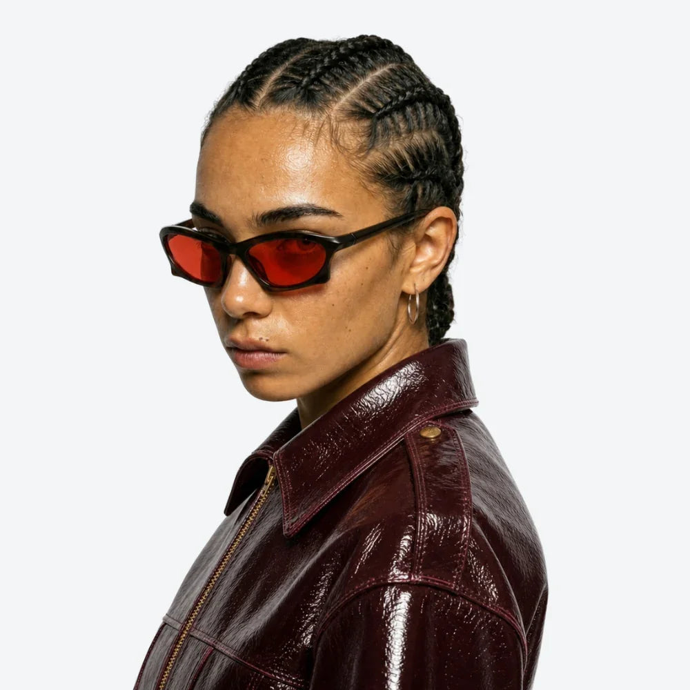 VYSER red-lens cat-eye sunglasses with black frames, styled with a burgundy leather jacket for streetwear edge.