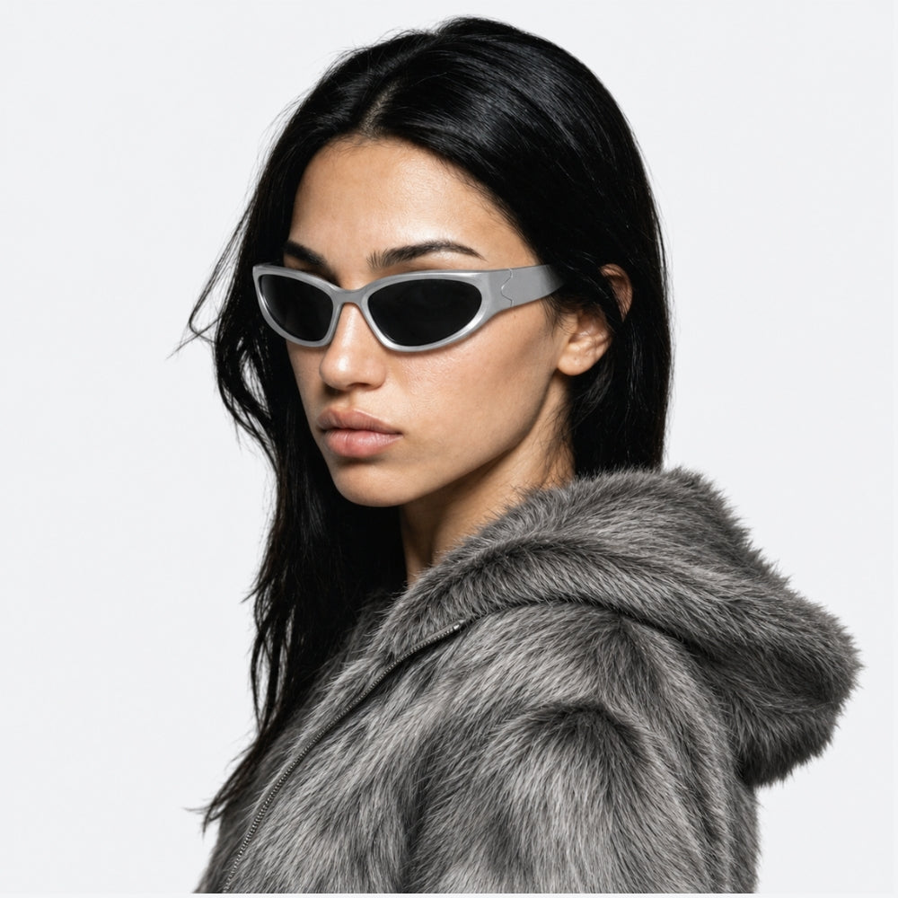 Woman wearing a fur coat and VYSER silver sunglasses with black lenses on a white background