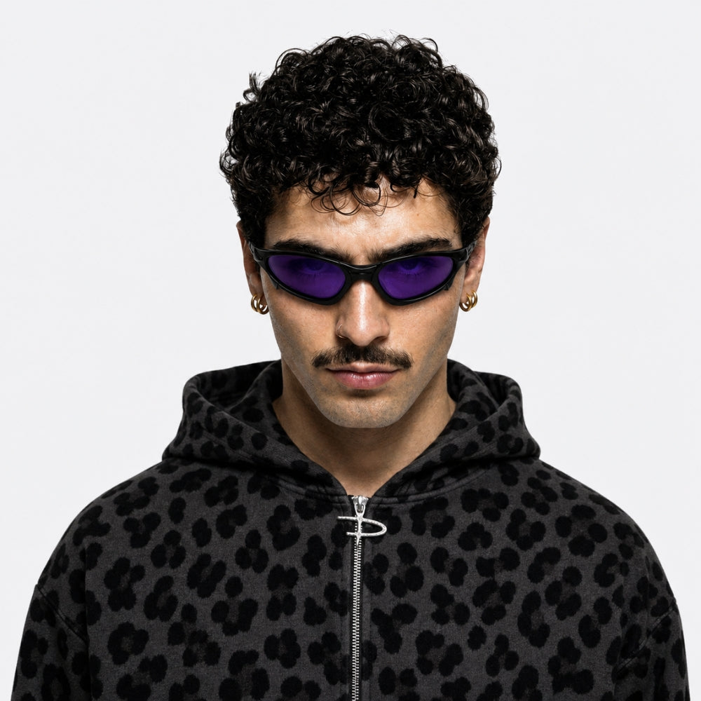 Person wearing a black leopard print hoodie and VYSER Sunglasses with a black frame and purple lenses on a white background
