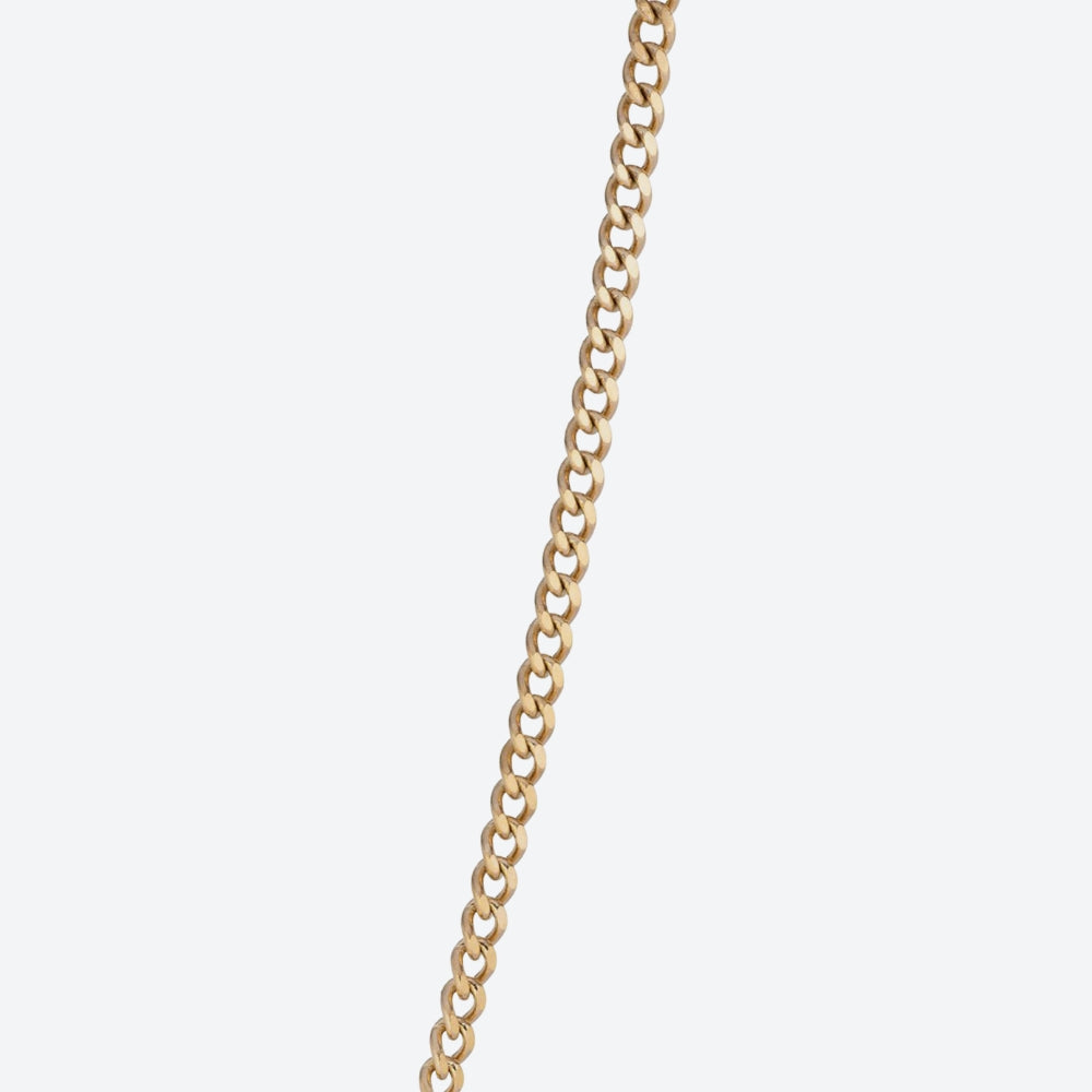 A close-up of a gold curb chain running vertically down the center of a light gray background.