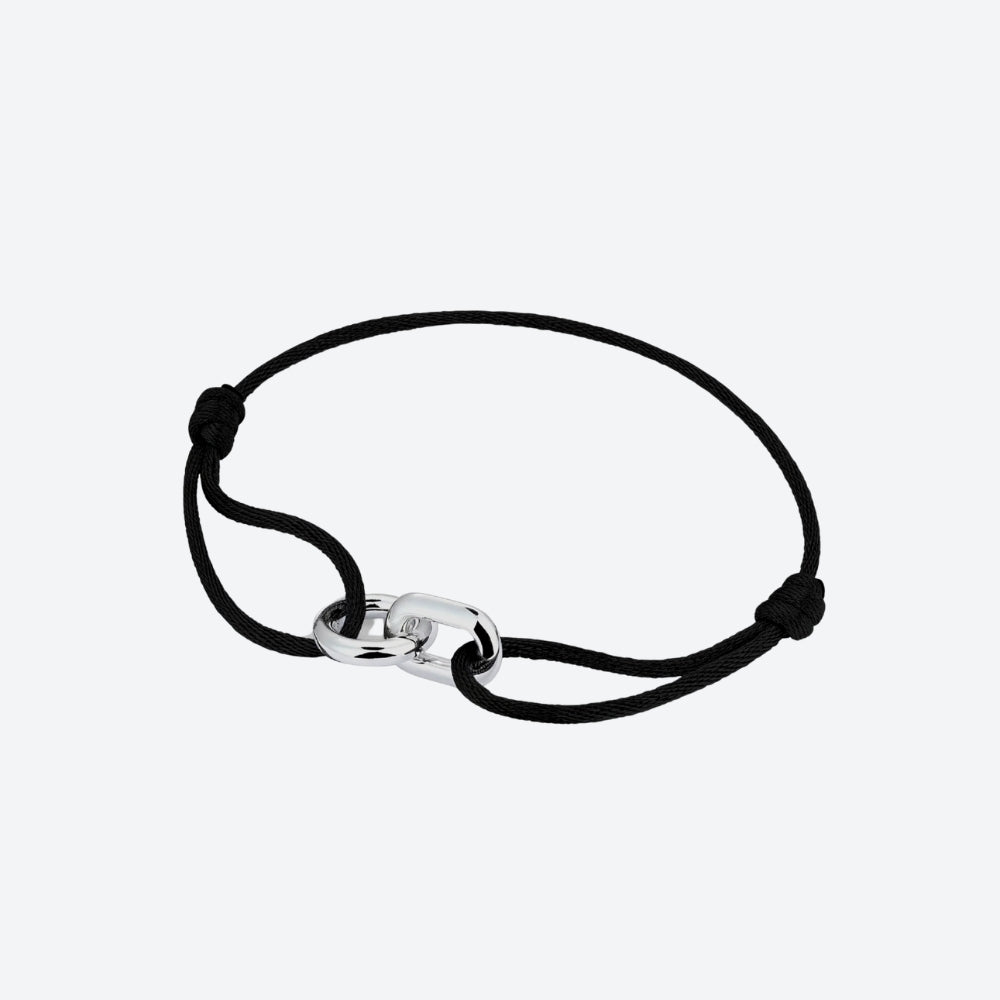 A black cord bracelet with a polished silver-toned interlocking link clasp, shown on a light gray background.