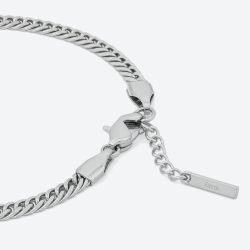 SILVER. A close-up of a silver Cuban chain bracelet with a lobster clasp, extender chain, and a brand tag, light gray background.