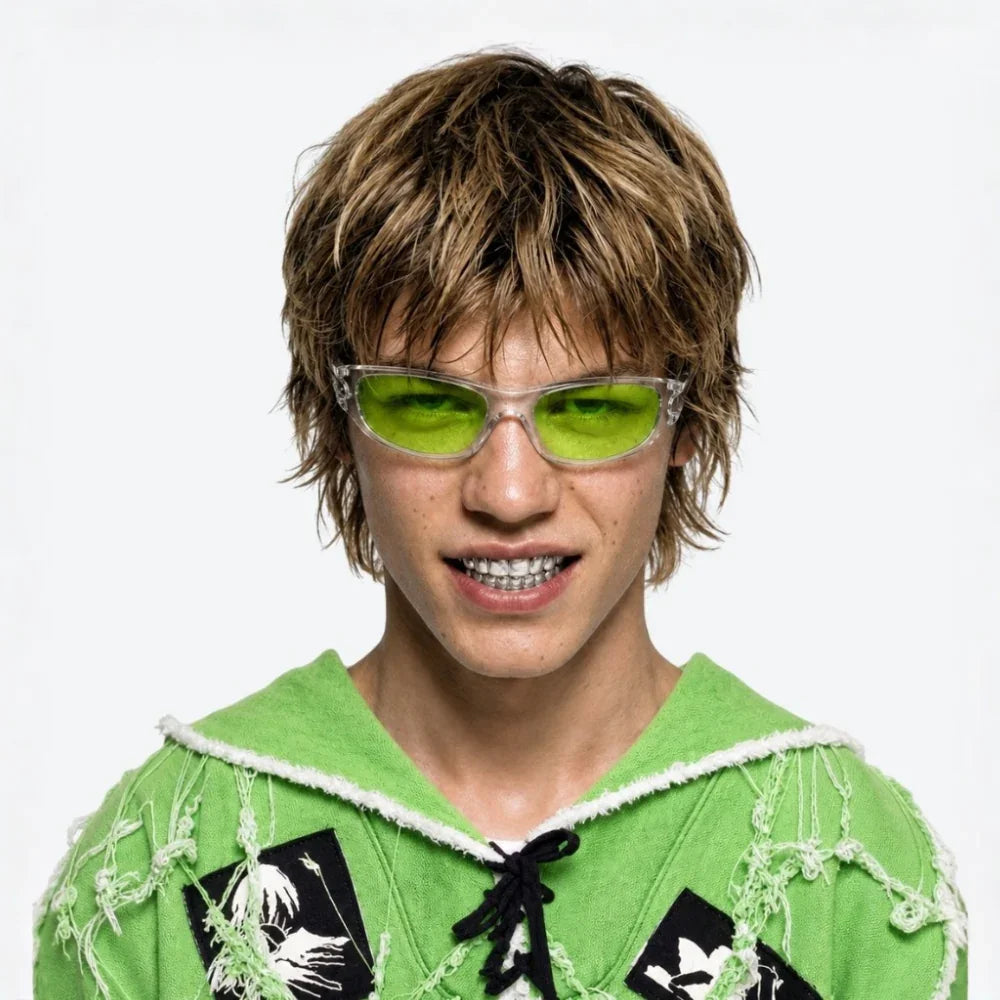 A close-up portrait of a person with short brown hair wearing VYSER sporty sunglasses with translucent gray frame and light green lenses, modern streetwear style.