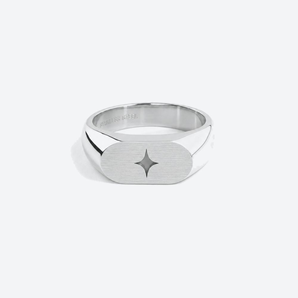 A silver-toned signet ring with a brushed finish and a small star inlay, shown on a light gray background.