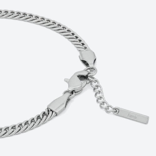 SILVER. A close-up of a silver Cuban chain bracelet with a lobster clasp, extender chain, and a brand tag, light gray background.