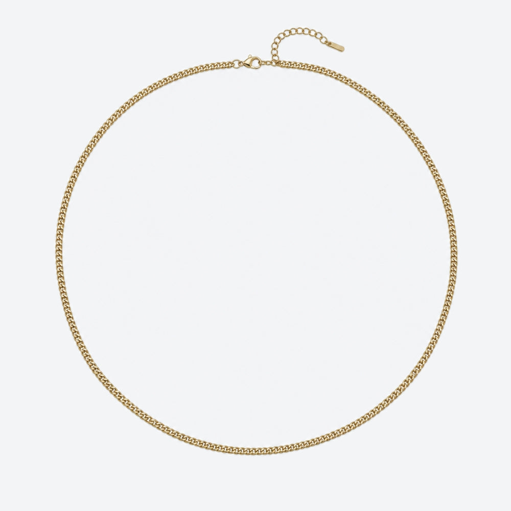 A delicate gold chain necklace with a curb link pattern, displayed in a circular shape against a clean, light gray background.