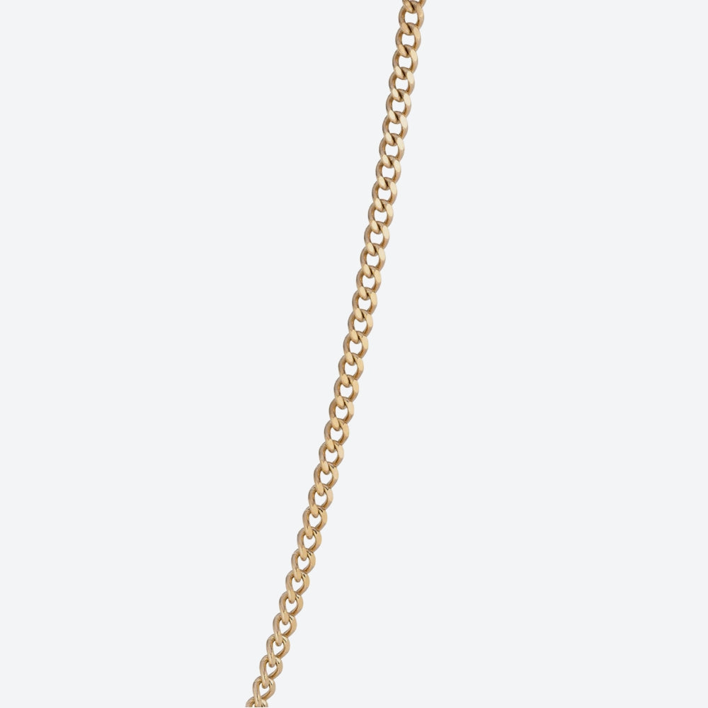 A close-up of a gold curb chain running vertically down the center of a light gray background.