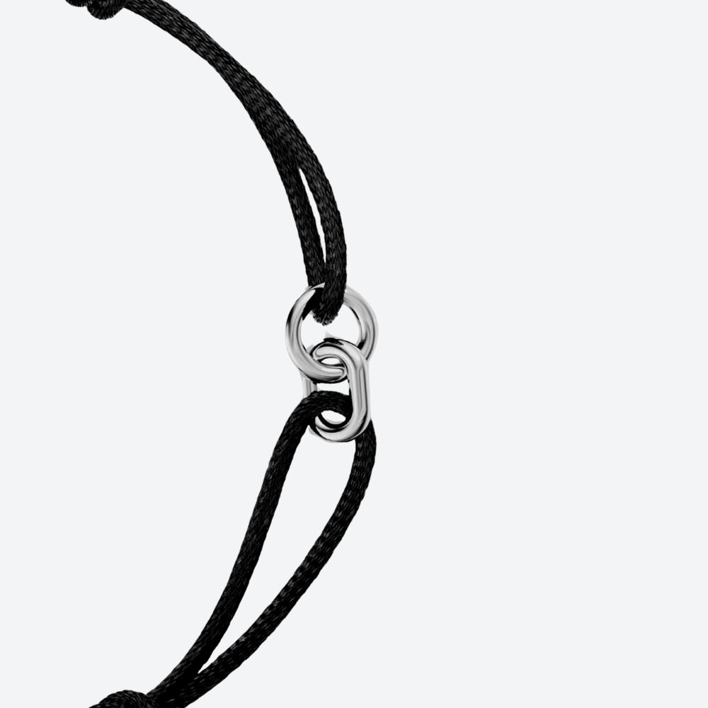 Close-up of a black braided cord bracelet with a polished silver interlocking rings clasp, set against a light gray background.