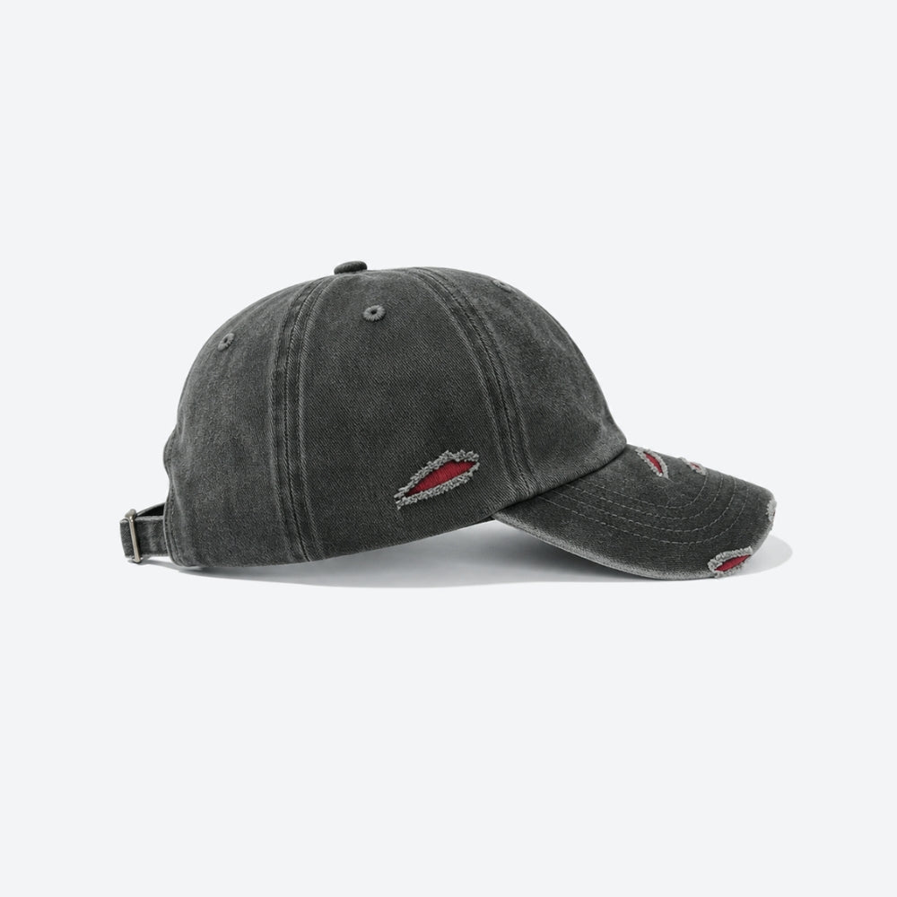 A washed black baseball cap with distressed details and small red embroidered logos on the front and brim, shown from a side profile on a light gray background.