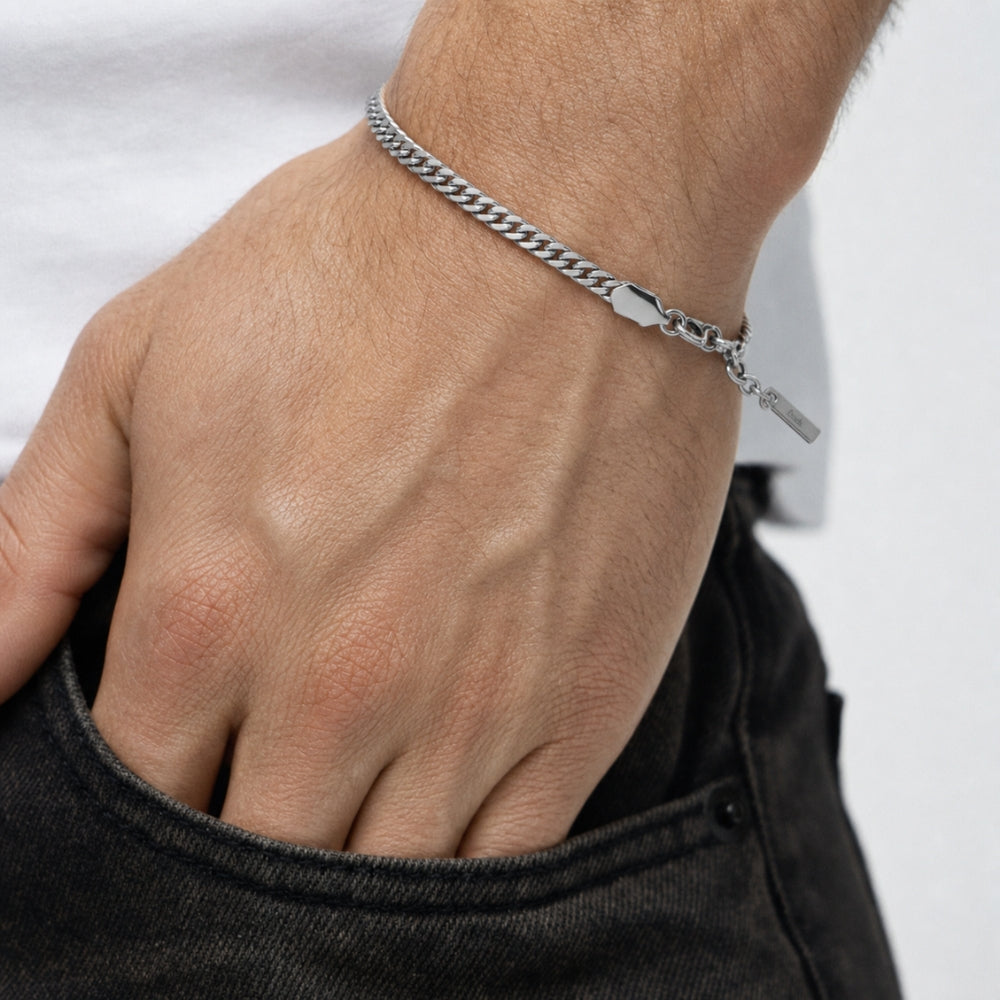 SILVER. A close-up of a silver Cuban chain bracelet with a lobster clasp and extender chain, light gray background.