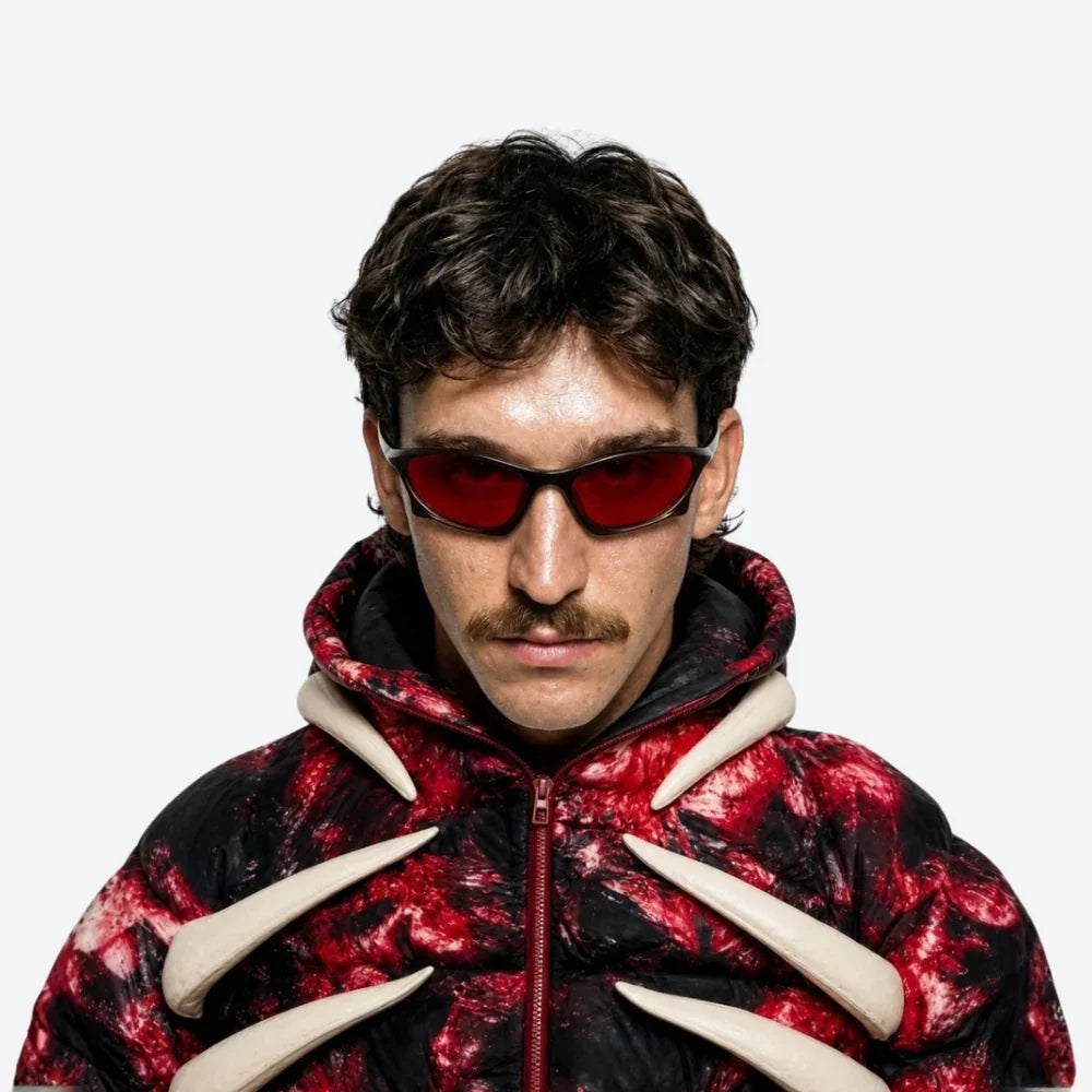 Person wearing a red and black jacket with animal-like features and VYSER dark brown acetate sunglasses with bold red lenses, sleek streetwear style
