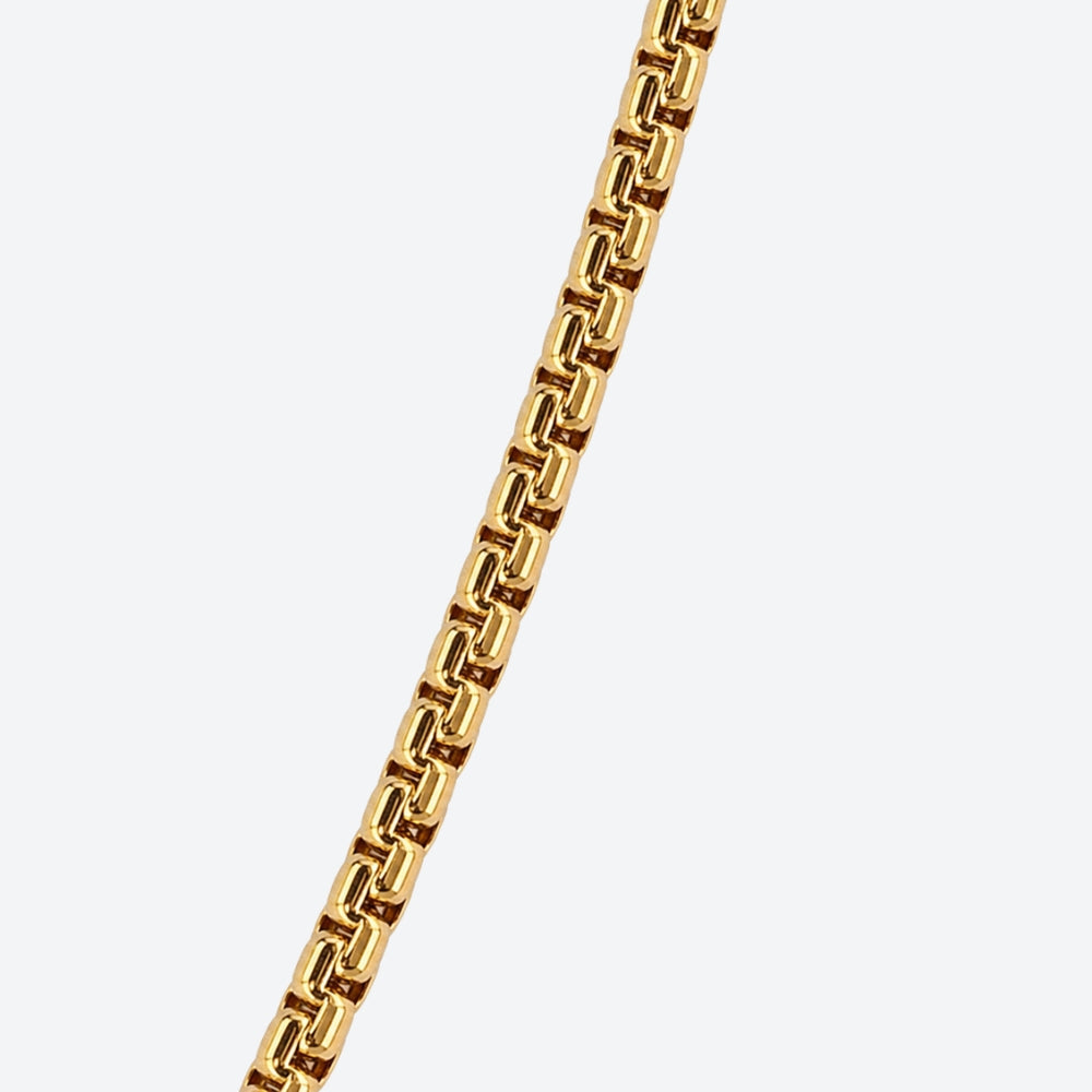 GOLD. A close-up of a gold box chain with interlocking links, on a light gray background.