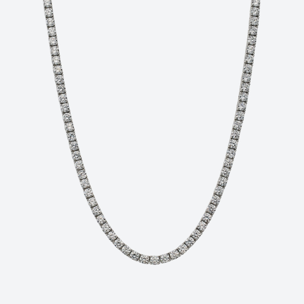 A silver-toned tennis chain necklace paved with small clear stones, shown against a plain light gray background.