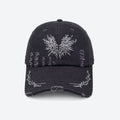 A black distressed baseball cap with a white embroidered moth on the front and thorn branch detailing along the brim, shown from the front