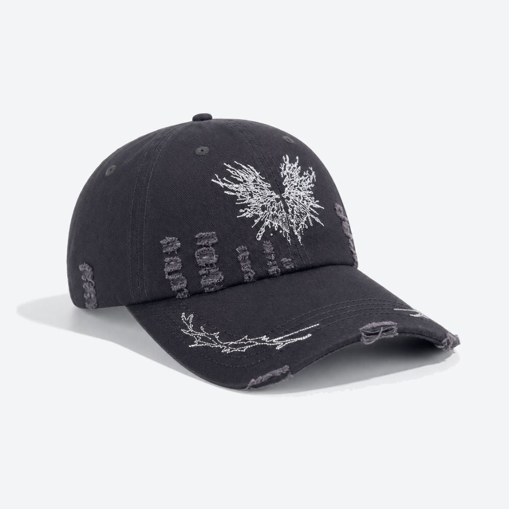 A black distressed baseball cap with a white embroidered moth, shown from a three-quarter angle revealing the ripped detailing on the crown